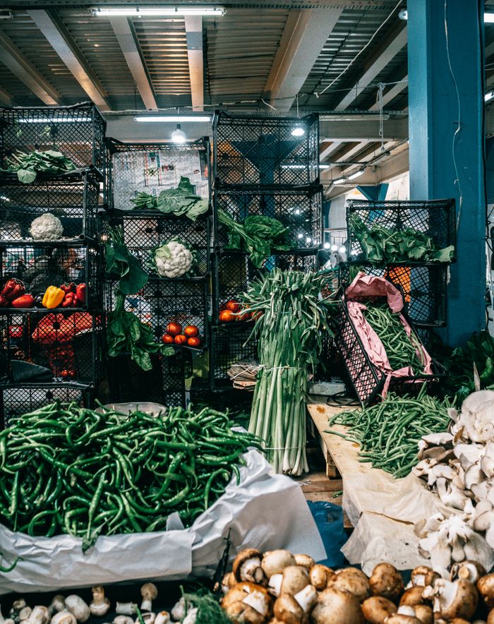 Assorted ripe vegetables including mushrooms green beans and cabbages kept in containers in modern grocery market warehouse